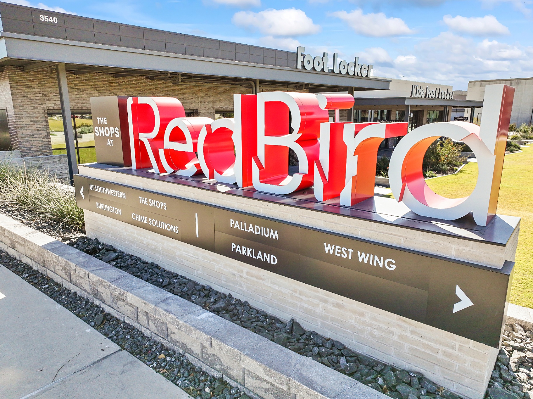 The Shops at Red Bird monument sign with Foot Locker and Kids Foot Locker storefronts
